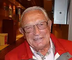 Photographie de Hjalmar Andersen en 2010. Il porte un manteau rouge.