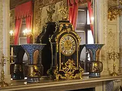 Photographie en couleur d'une horloge ancienne sur le rebord d'une cheminée.