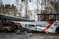Photo couleur de plusieurs avions criblés de balles, à côté d'un fourgon carbonisé.