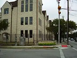  Photographie d'une école aux murs blancs entourée d'une grille noire.