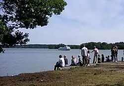 Photo de gens assis au bord d'un cours d'eau