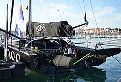 Vue trois quarts arrière d'un voilier noir, amarré dans le port.