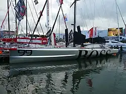 Vu de trois quarts avant, voilier argenté amarré à un ponton.