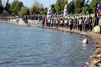 Photo en couleur, on voit des triathlètes en combinaison qui attendent le départ.