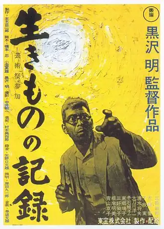 Affiche d'un film avec des inscriptions en japonais. Un homme avec des lunettes au visage terrifié pointe du doigt quelque chose devant lui, qu'on ne voit pas. Il se situe devant un fond jaune et devant le Soleil.
