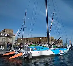 Vu de trois quarts arrière, voilier blanc et bleu amarré au ponton.
