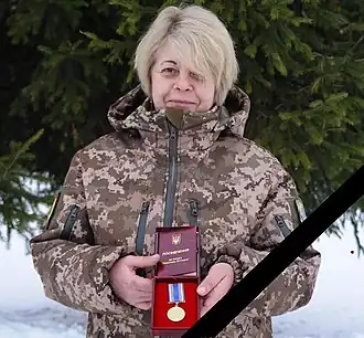 Femme blonde en uniforme, tenant une boîte avec une médaille à l'intérieur