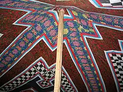 Mât central dans une tente décorée en patchwork.