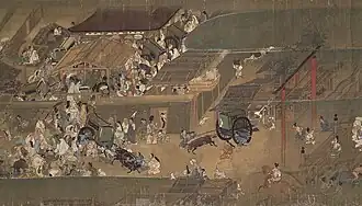 Foule très dense et animée qui occupe tout l’espace, se pressant autour de plusieurs petits bâtiments.