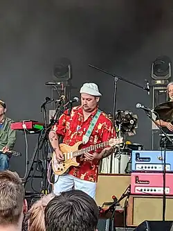 Une photo d'Isaac Brock en chemise hawaïenne jouant de la guitare