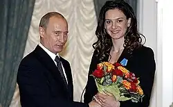 Photographie d'Isinbayeva en costume noir tenant un bouquet de fleurs jaunes et rouges