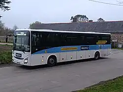 Photo du côté droit d'un car blanc ayant une livrée bleue.