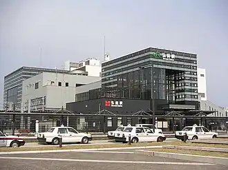Photo couleur d'une entrée de gare avec une station de taxi à l'avant-plan