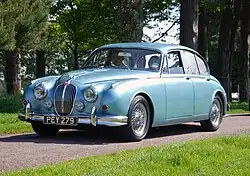Une voiture des années 1960, lignes courbes, détails chromés, phares ronds.