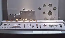 Photo couleur d'objets anciens (poteries, outils, ornements religieux) exposés derrière une vitrine.