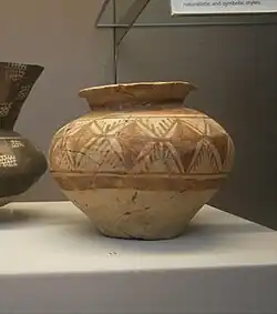 Petit vase en argile peint de différents motifs géométriques noirs et rouges pâle.