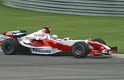 Photo de côté d'une monoplace rouge et blanche en piste