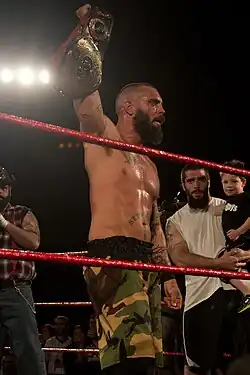 Catcheur soulevant sa ceinture aux côtés de son frère.