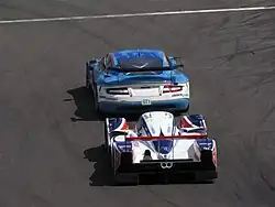 Photographie de deux voitures de grand tourisme et de sport-prototype, l'une derrière l'autre, vue de derrière