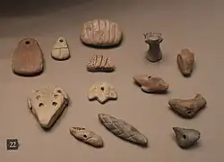 Jetons en argile aux formes diverses, incisés de motifs linéaires et de signes ronds.