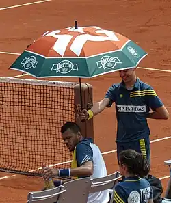 Ramasseur abritant Jo-Wilfried Tsonga sous un parasol en 2013.