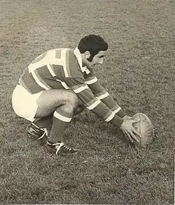 Photo noir et blanc d'un joueur en maillot rayé en train de placer le ballon au sol avant une pénalité
