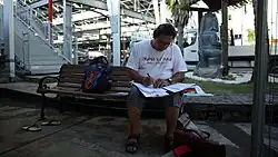 Un homme assis sur un banc, lisant des feuilles un stylo à la main