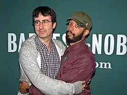 Oliver et Cenac enlacés pour la photo sur un fond vert foncé