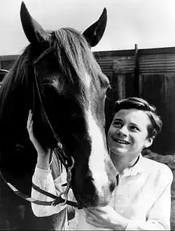 Photographie en noir et blanc avec la tête d'un cheval et un garçon à chapeau de cow-boy.