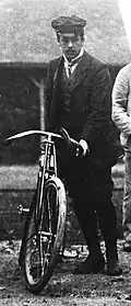 Photo d'un homme en costume tenant une motocyclette.