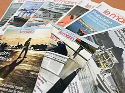 Des exemplaires papiers du journal Le Marin empilés sur une table.