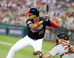 Photographie de côté de deux joueurs de baseball en match, l’un à la batte, l’autre en tant que receveur.