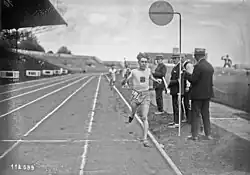 Photographie en noir et blanc d'un coureur à pied à l'arrivée de sa course dans un stade.