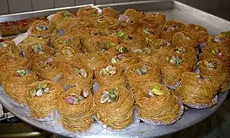 Une variante égyptienne traditionnelle de kunafa, où des brins de kunafa déchiquetés enveloppent un mélange de noix assorties et sont ensuite trempés dans du sirop sucré