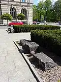 Des pierres provenant du monument détruit en 1940, situées en face du monument actuel reconstruit.