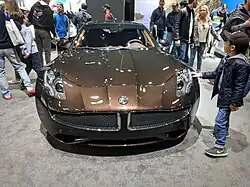 Photo de l'avant d'une voiture de luxe marron dans un stand d'exposition.
