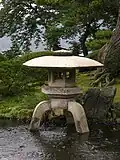 Yukimi-dōrō à trois pieds. Un pied repose à terre, les deux autres dans l'eau.