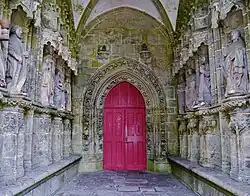 Intérieur du porche. De chaque côté sont alignées les statues des apôtres. Au fond, une porte en tiers-point.