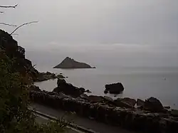 Photo prise de la côte où apparaît non loin une petite île rocheuse.