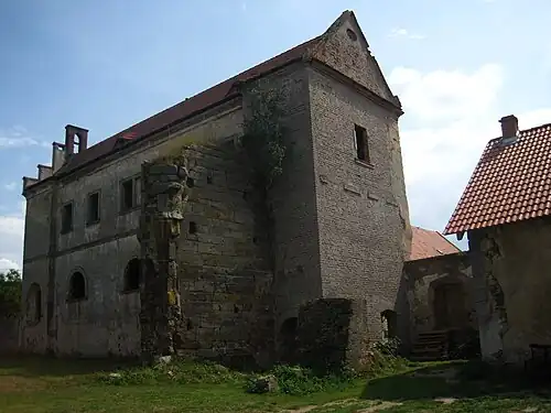 Photographie couleur d'un mur en pierre de taille jouxtant un ancien bâtiment en briques.