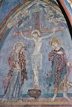 Fresque colorée médiévale représentant une crucifixion avec un homme et une femme de part et d'autre de Jésus crucifié.