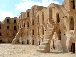 Photo d'une barre d'habitation dans le désert avec de nombreuses ouvertures et des escaliers en façade.