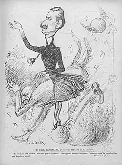 Dessin sépia de deux hommes présentés dans un tourbillon de bulletins de vote ; l’un, jeune, mince et moustachu, arbore une veste gonflée et tente de se maintenir en équilibre sur une boule de contrôle, tandis que l’autre, plus âgé et à la barbe blanche, se tient courbé, les pans de sa queue-de-pie redressés et le regard en direction de celui qui semble être son adversaire