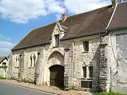 Mur gouttereau donnant sur la rue avec contreforts, fenêtres géminées et porche massif