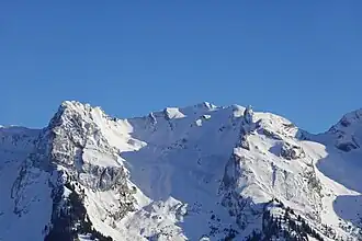 La tête Pelouse (au centre) avec à sa droite le mont Rachais et son aiguille dominant la combe du Grand Crêt (au centre) la séparant de la roche Perfia (à gauche).