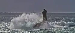Des lames se brisant et écumant sur un phare pendant un coup de vent.