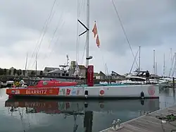 un bateau vu de profil, sa coque est blanche et rouge avec le logo "Laboratoires de Biarritz" à l’arrière