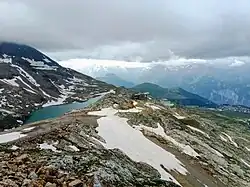 Vue estivale depuis le dôme des Petites Rousses au nord de la gare d'arrivée du téléphérique accolée à la gare de départ du téléphérique du Pic-Blanc ; l'Alpe d'Huez est visible sur le bord droit.