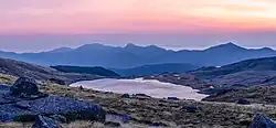 Dans la lumière douce d'un lever de soleil, une modeste étendue d'eau se réveille au milieu des montagnes.