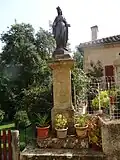 Statue de l'Immaculée Conception. Sur le socle sont représentés : une ancre (symbole de l’espérance, l'une des trois vertus théologales), le monogramme marial composé des lettres A et M entrelacées, initiales de l’Ave Maria, et le Cœur Immaculé de Marie